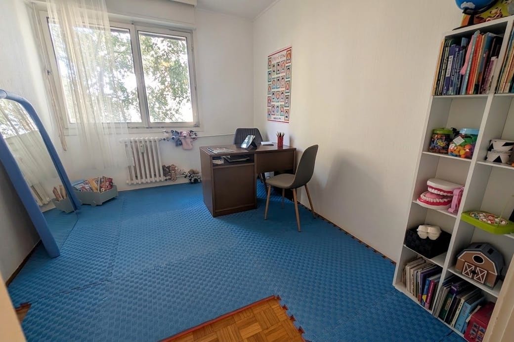 Soba sa radnim stolom, velikim ogledalom, posterom sa vežbama za jezik i usne i velikim modelom zuba na polici